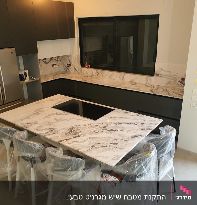 משטחי שיש במטבח מודרני עם כיסאות עטופים בניילון